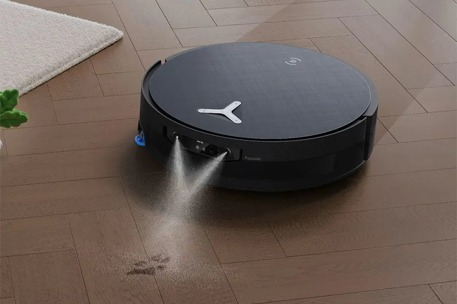 The Ecovacs Deebot X12 OmniCyclone robot vacuum targeting a paw print on the floor with two jets of cleaning solution.