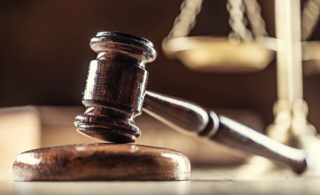 A judge's gavel with scales in the background.