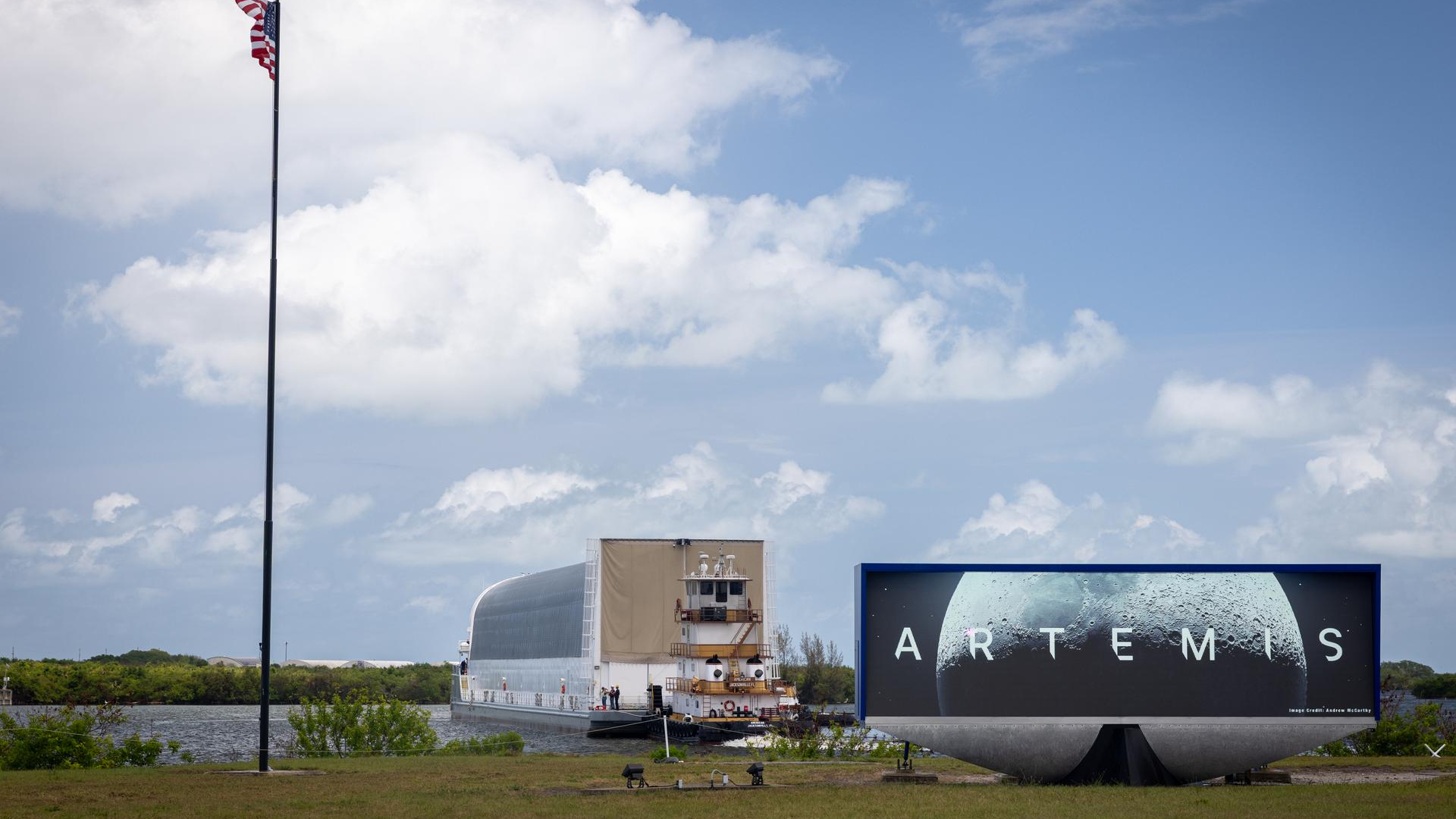 a large barge pulls up to a grassy bank next to a sign that says &amp;quot;artemis&amp;quot;