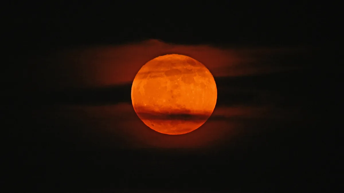 A Strawberry Moon rises over a city skyline