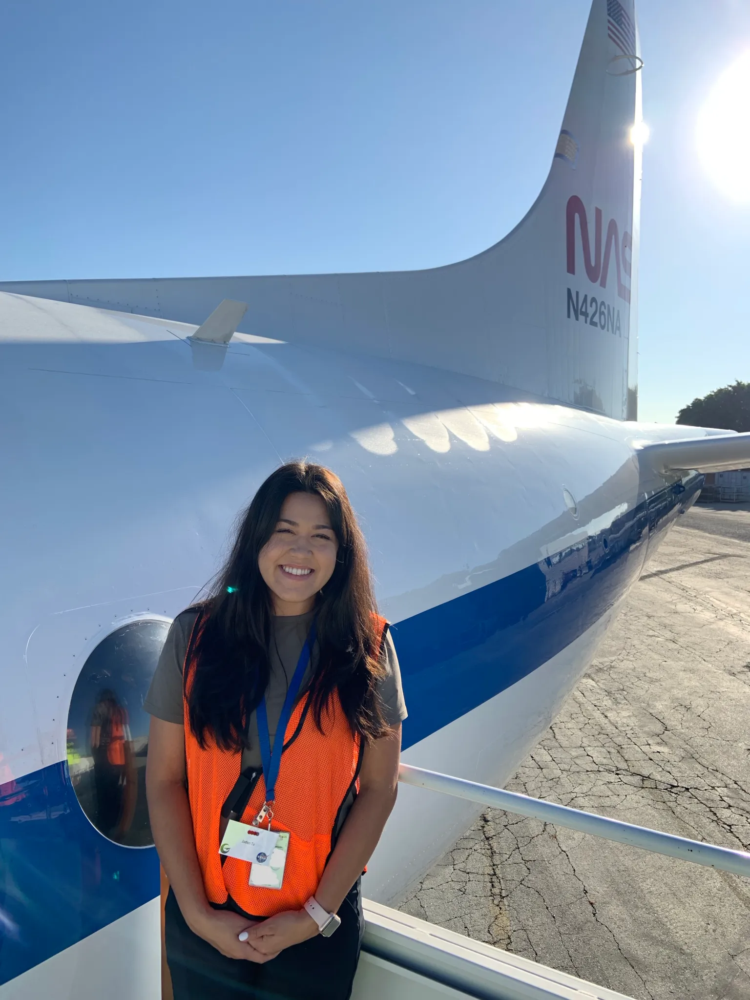 Image of NASA Ames scientist Jaden Ta wearing a safety jacket while standing in front of a NASA aircraft.