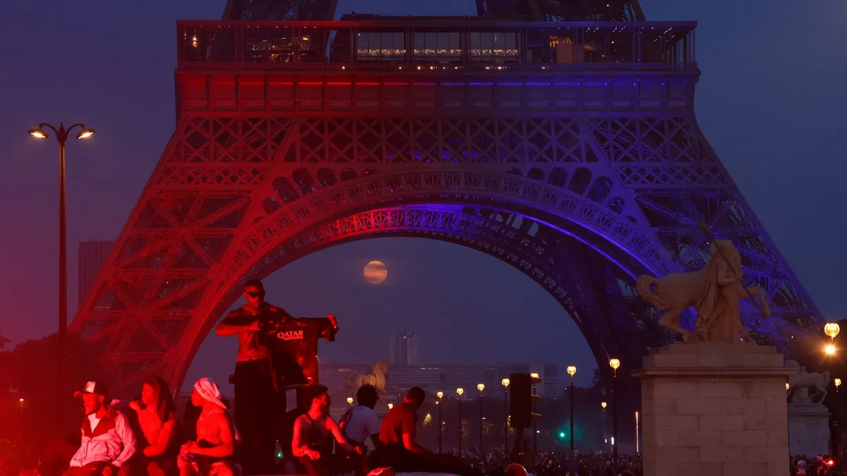 The moon glows between the Eiffel Tower's steel legs as fans celebrate PSG's Champions League victory. Photo by Gary Hershorn/Getty Images