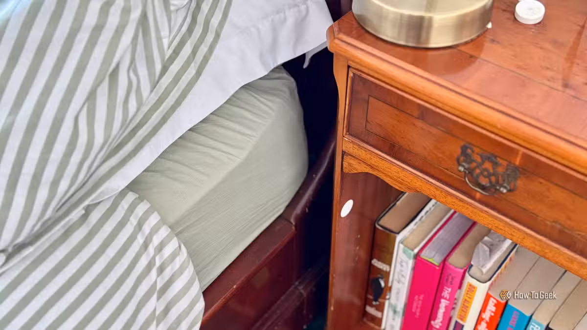 An NFC tag stuck to the underside of a nightstand, hidden from view but within phone-tap range.