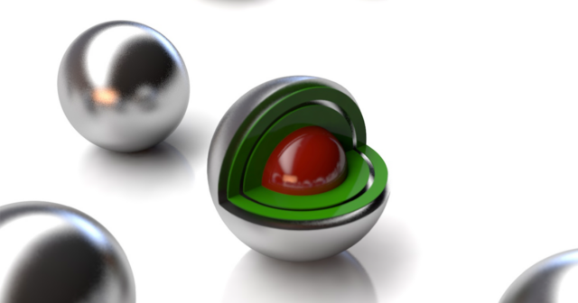 Image of a set of silvery balls, one of which has a cutaway showing layers of green and a red core.