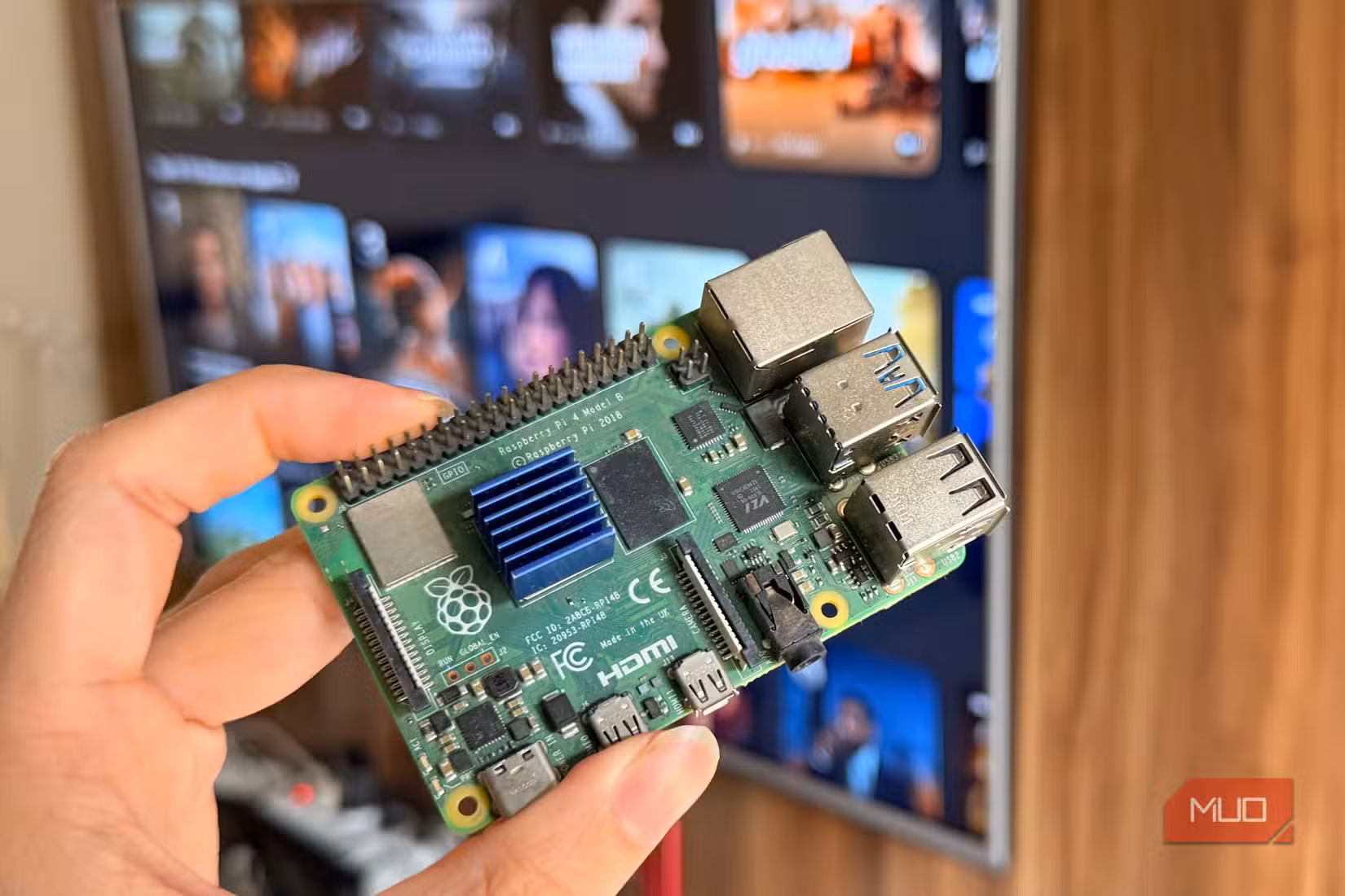 Hand holding a Raspberry Pi 4 in front of a smart TV